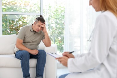 Overweight man having consultation with nutritionist in clinic, selective focus