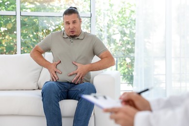 Photo of Overweight man having consultation with nutritionist in clinic, selective focus