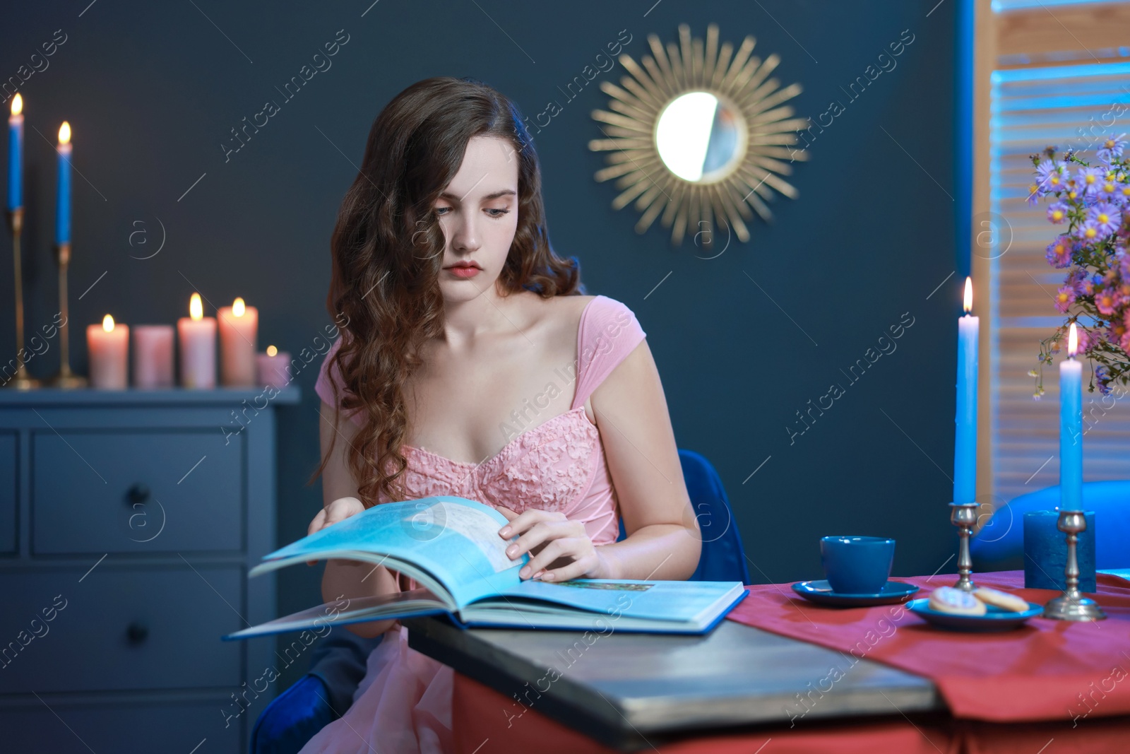 Photo of Beautiful young woman reading book at table in room. Fashion vintage style portrait