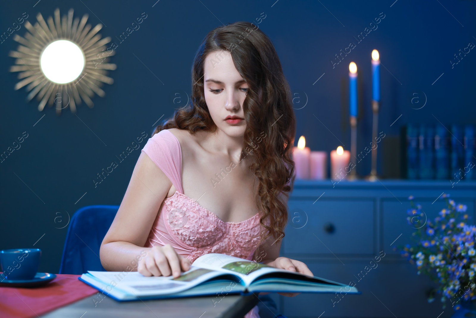 Photo of Beautiful young woman reading book at table in room. Fashion vintage style portrait