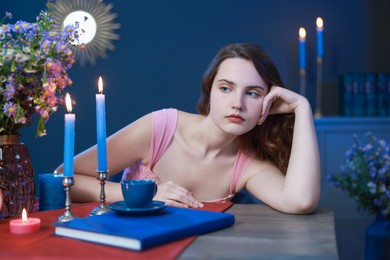 Beautiful young woman posing at table in room. Fashion vintage style portrait