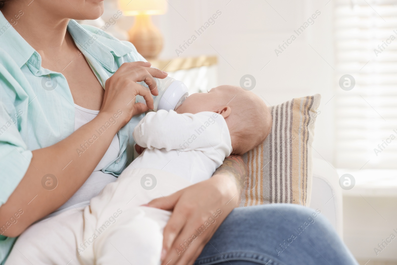 Photo of Mother feeding her cute baby indoors, closeup