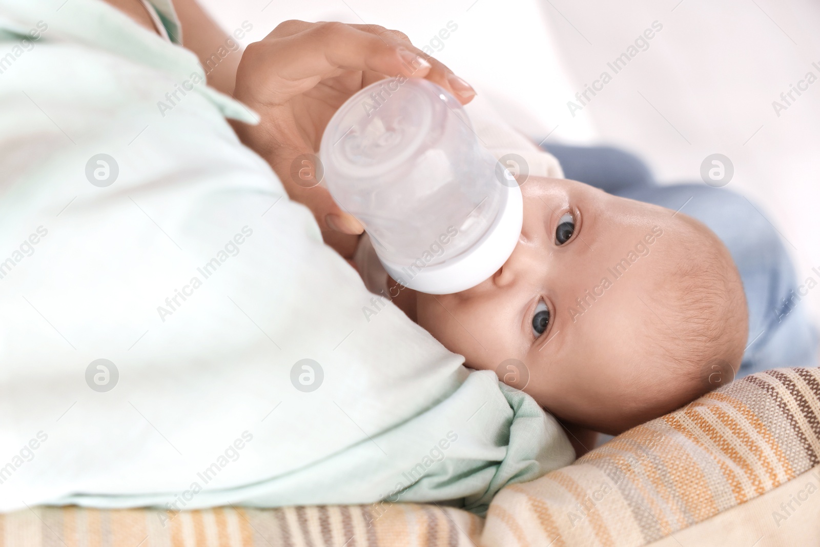 Photo of Mother feeding her cute baby indoors, closeup