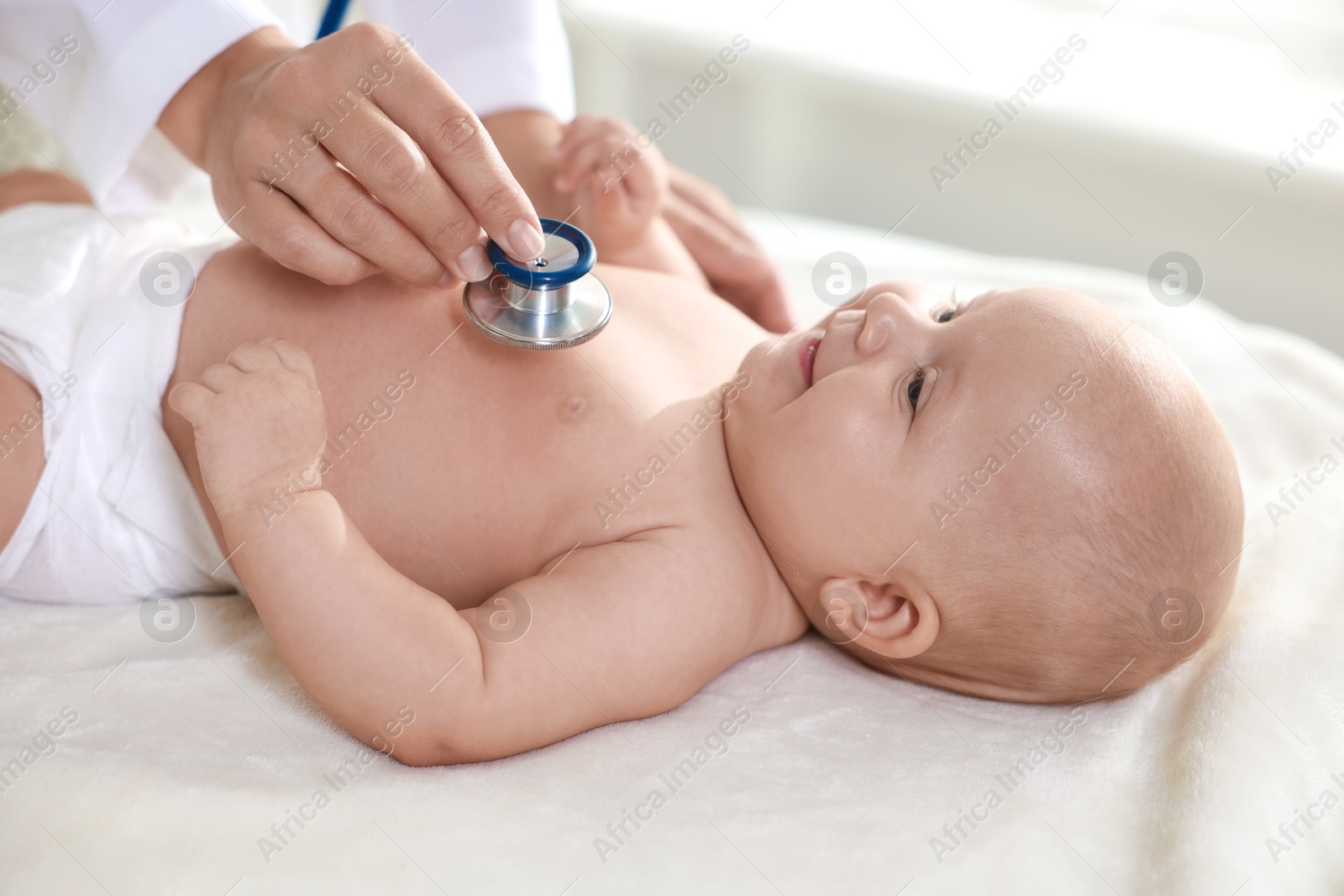 Photo of Pediatrician examining little child with stethoscope in clinic, closeup. Checking baby's health