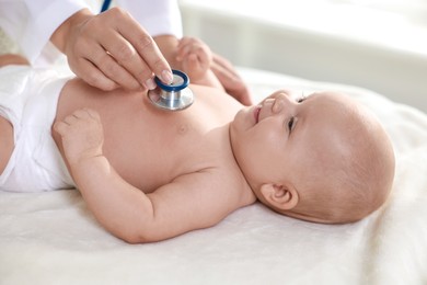 Photo of Pediatrician examining little child with stethoscope in clinic, closeup. Checking baby's health