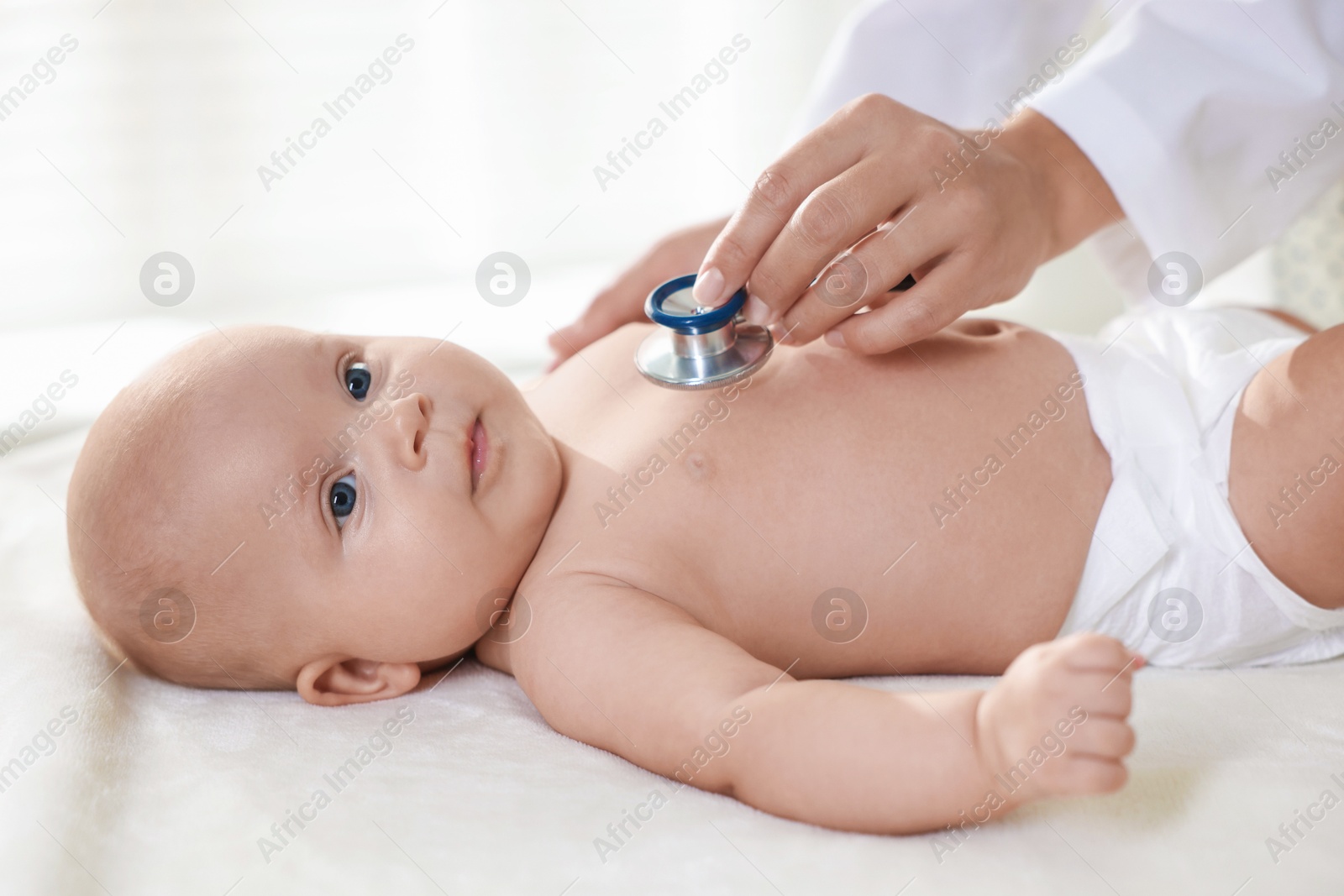 Photo of Pediatrician examining little child with stethoscope in clinic, closeup. Checking baby's health