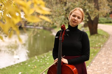 Photo of Beautiful young woman with cello in park