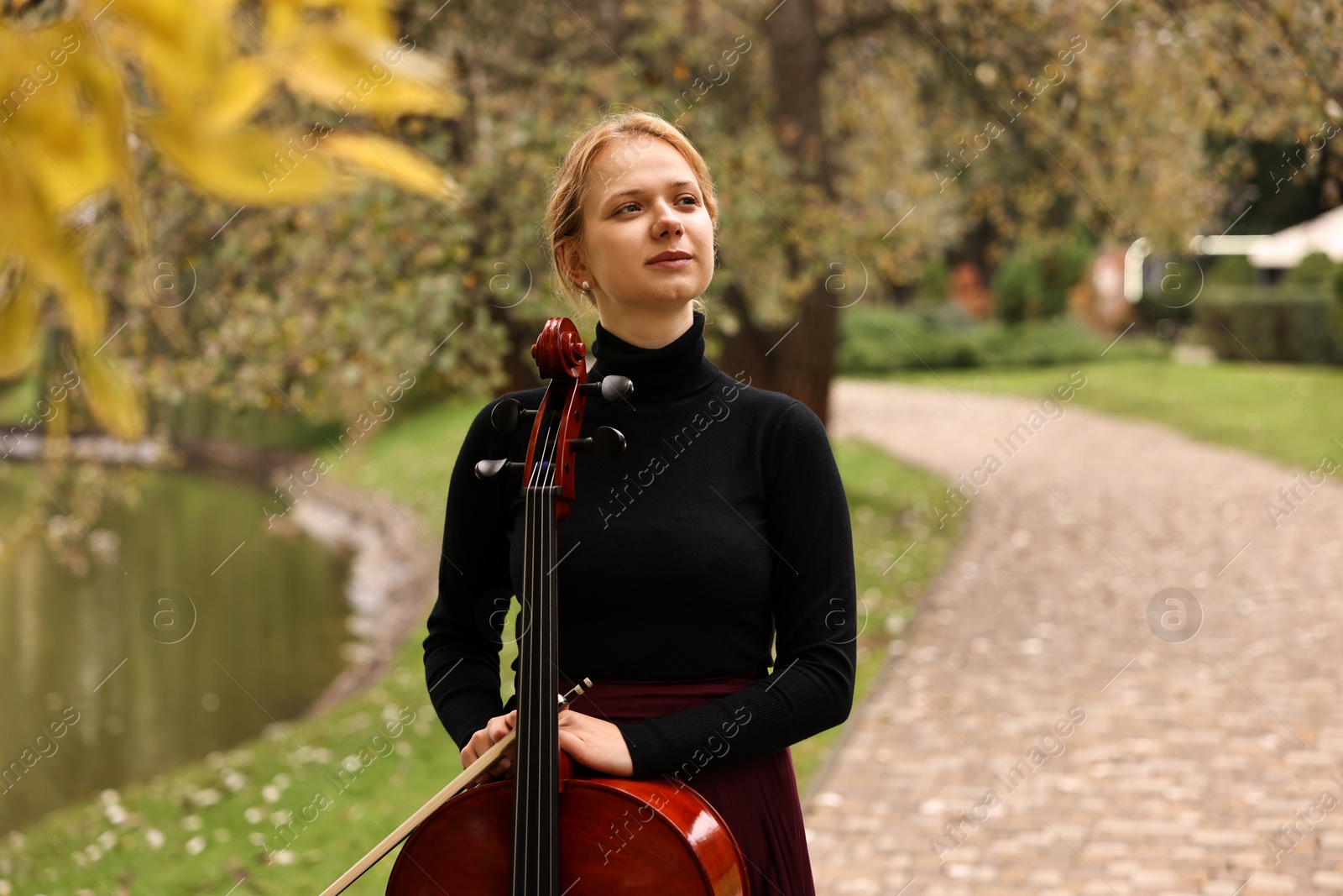 Photo of Beautiful young woman with cello in park