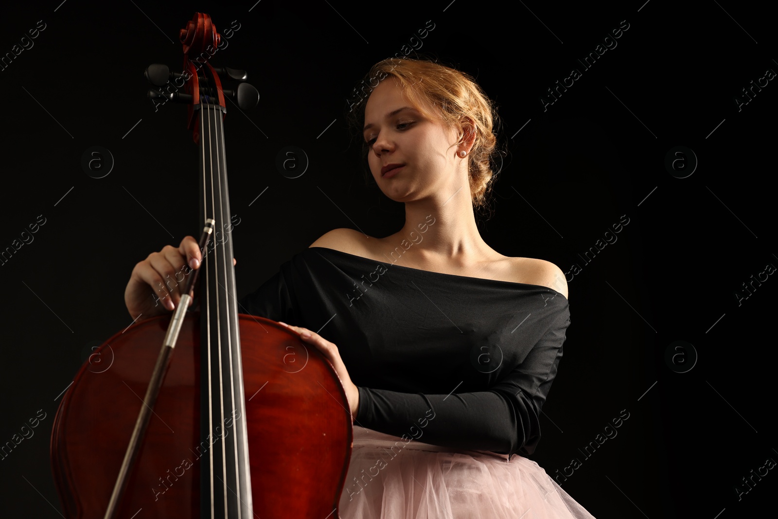 Photo of Beautiful young woman with cello on black background