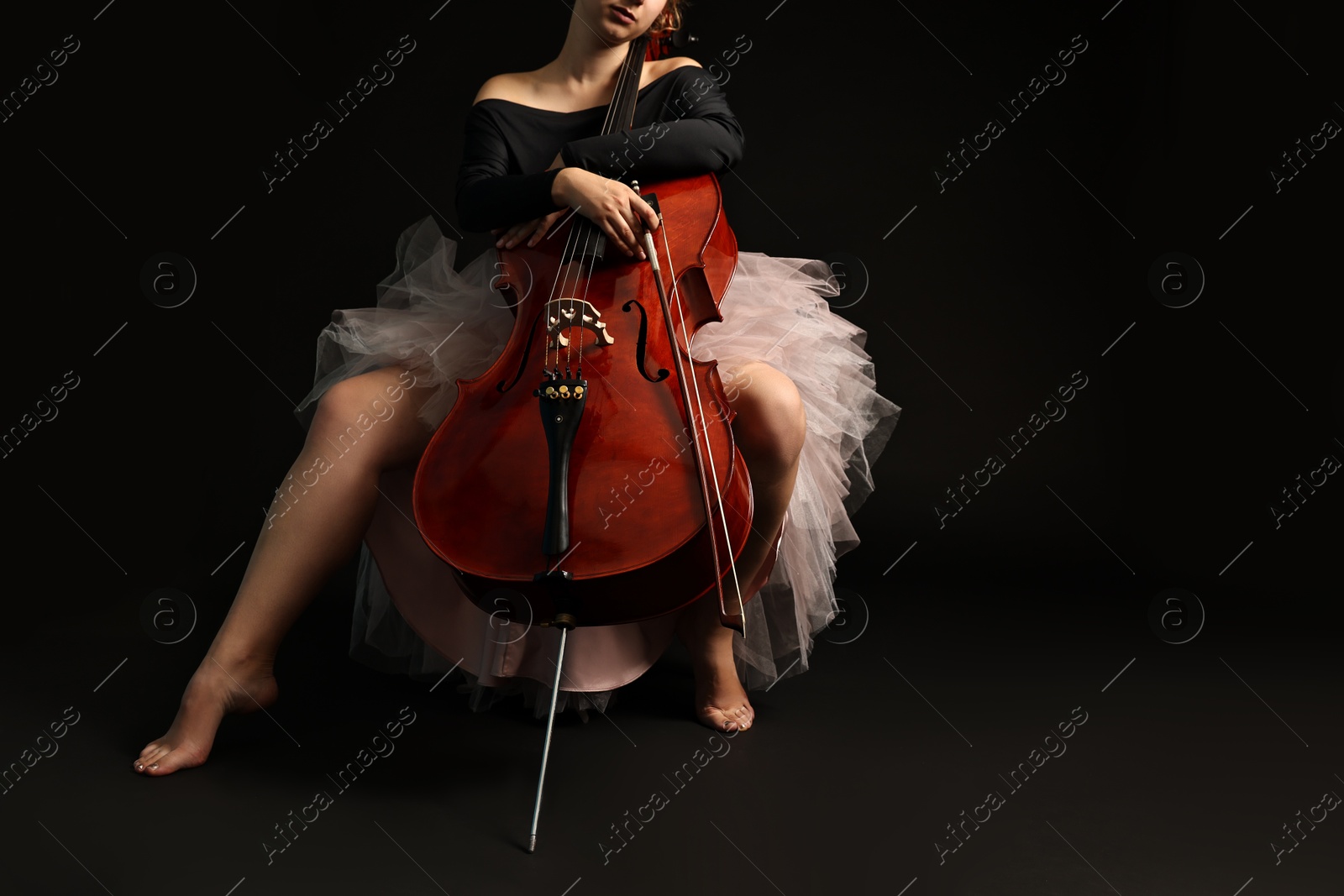 Photo of Young woman with cello on black background, closeup. Space for text