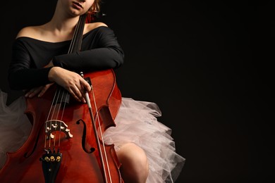 Photo of Young woman with cello on black background, closeup. Space for text