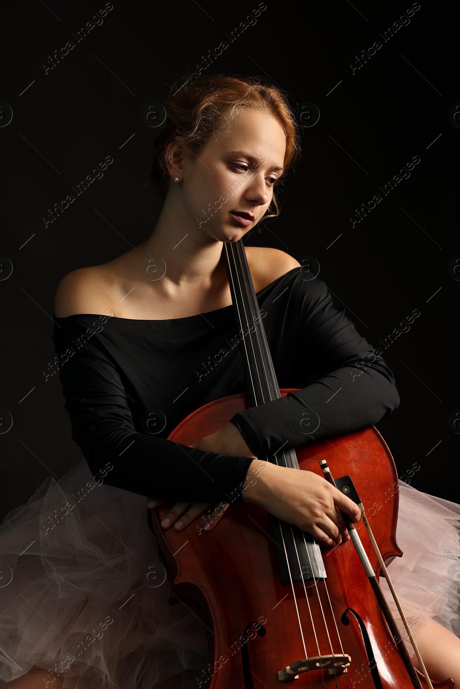 Photo of Beautiful young woman with cello on black background