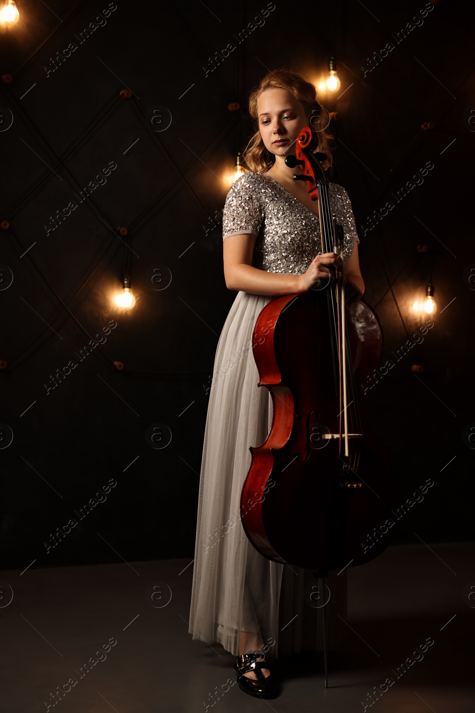 Photo of Beautiful young woman with cello on stage. Classic musical instrument