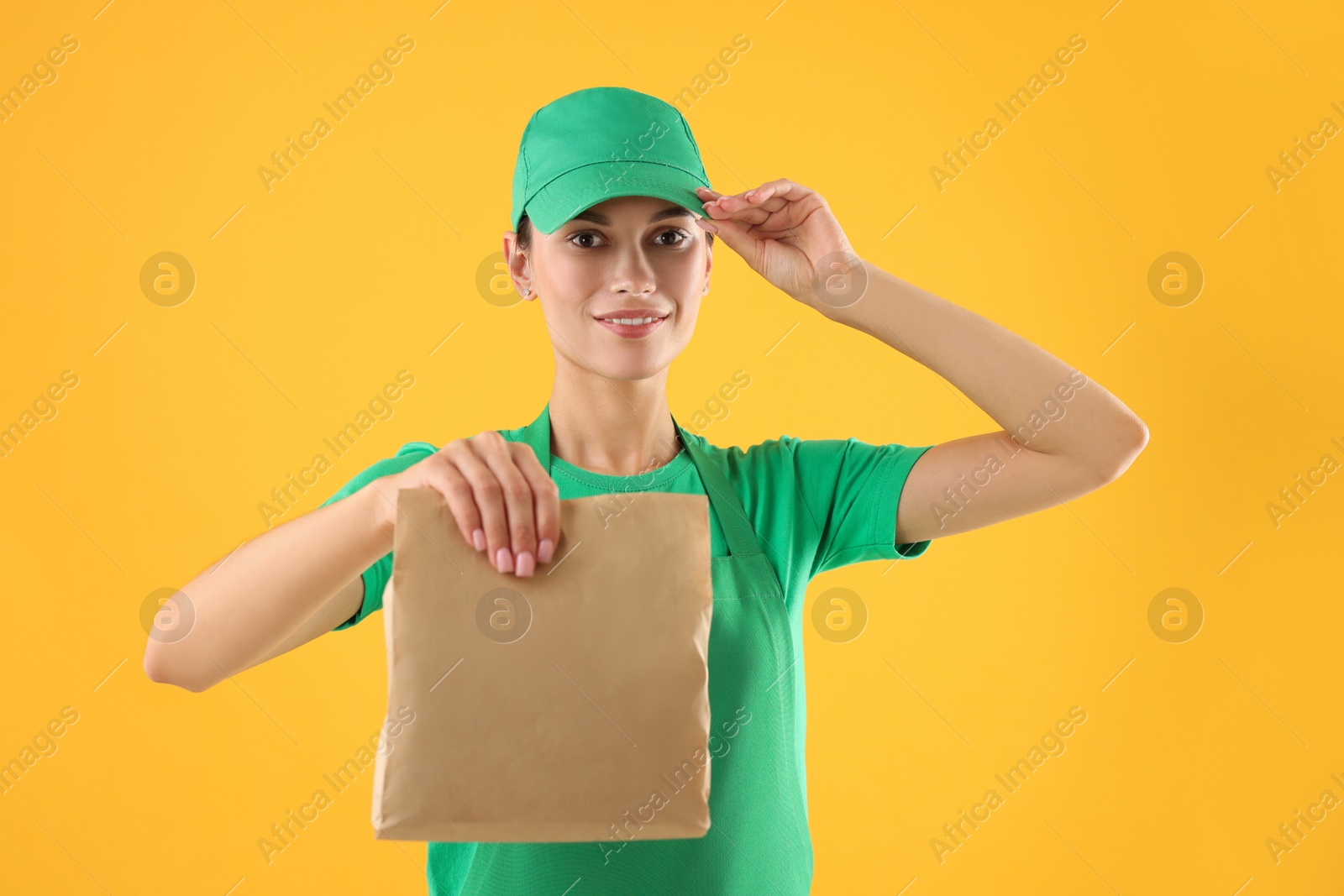 Photo of Fast-food worker with paper bag on orange background