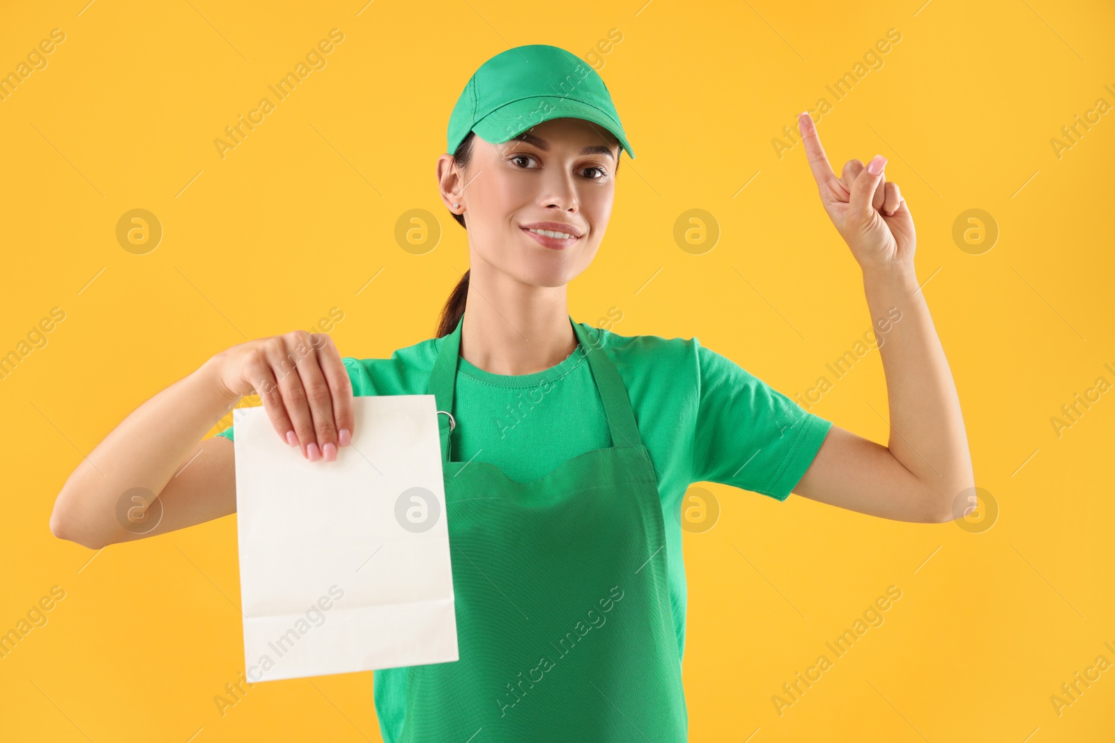 Photo of Fast-food worker with paper bag on orange background