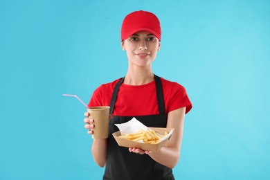 Photo of Fast-food worker with paper cup and fries on light blue background