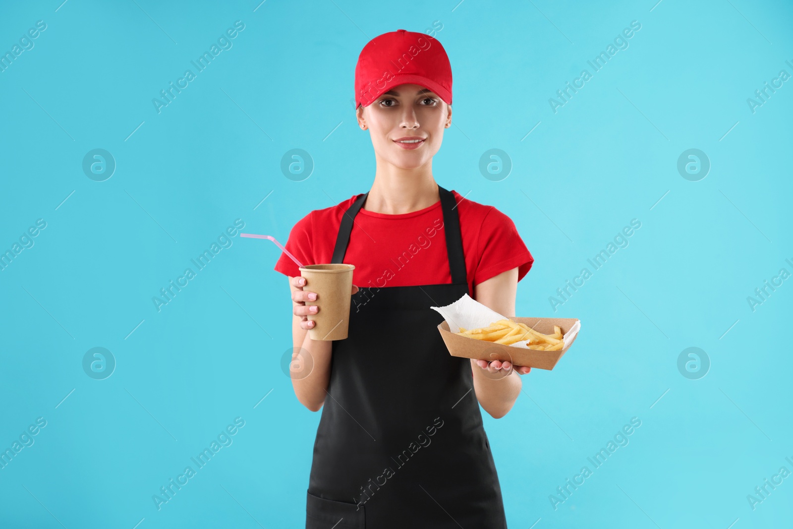 Photo of Fast-food worker with paper cup and fries on light blue background