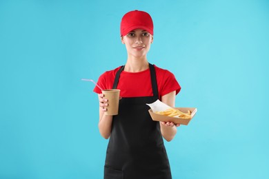 Fast-food worker with paper cup and fries on light blue background