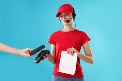 Photo of Fast-food worker taking payment from client via terminal on light blue background, closeup