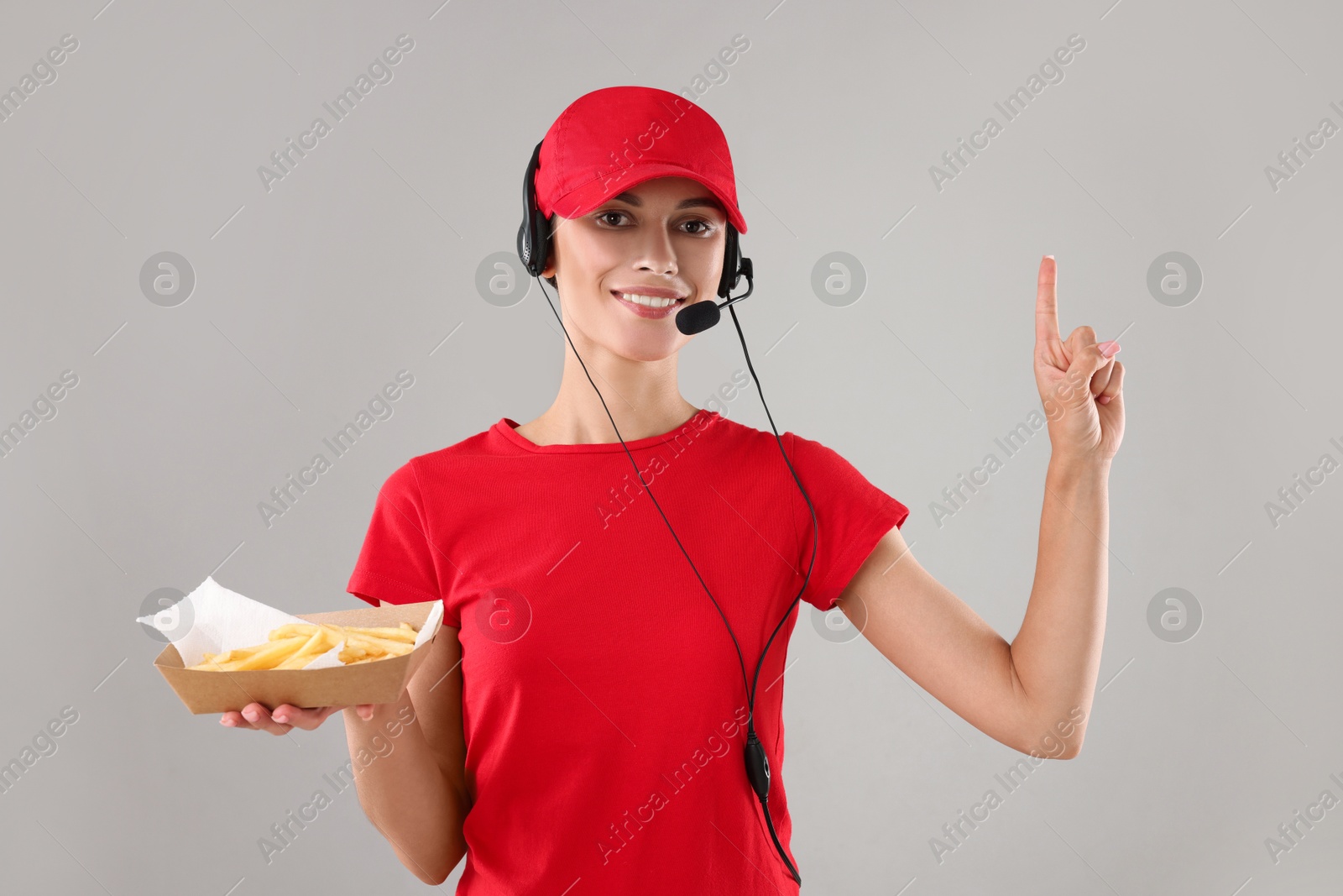 Photo of Fast-food worker holding paper container with fries on gray background