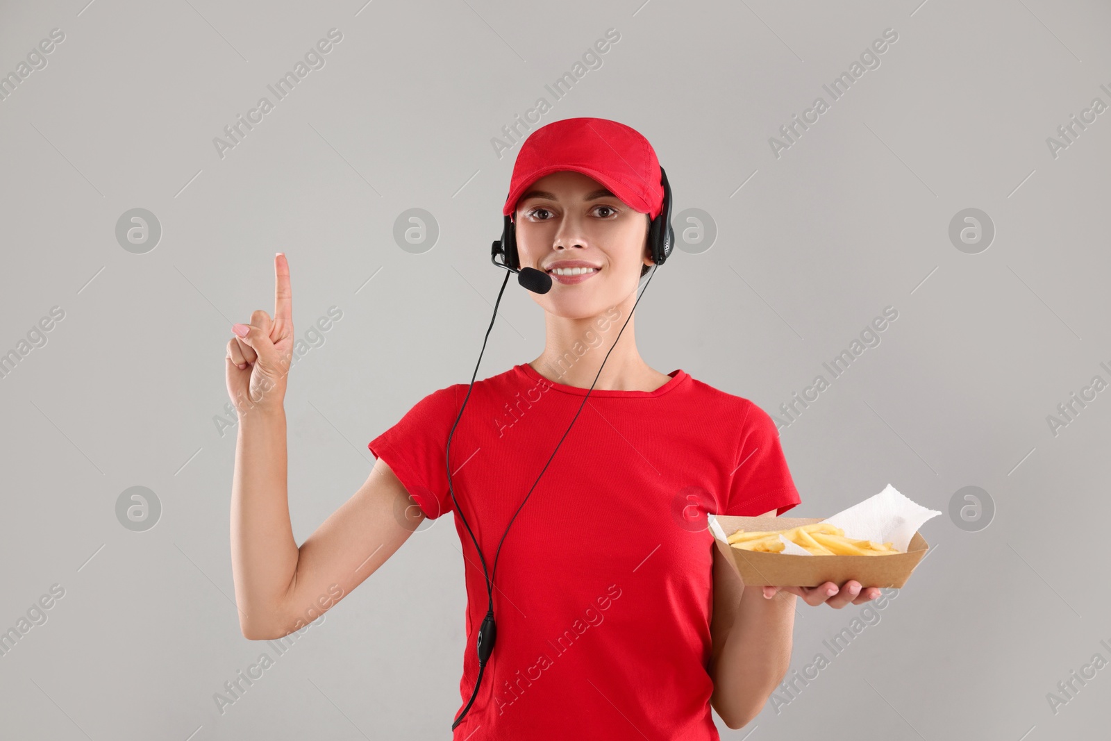 Photo of Fast-food worker holding paper container with fries on gray background