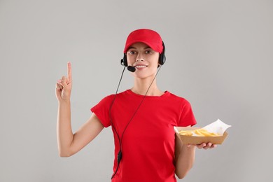 Fast-food worker holding paper container with fries on gray background