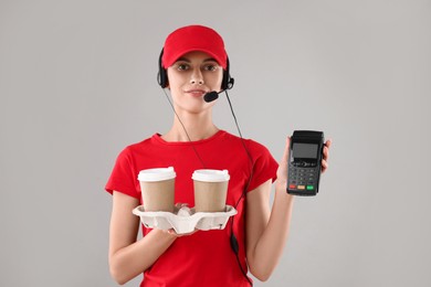 Photo of Fast-food worker with paper cups and payment terminal on gray background