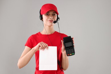 Photo of Fast-food worker with paper bag and payment terminal on gray background