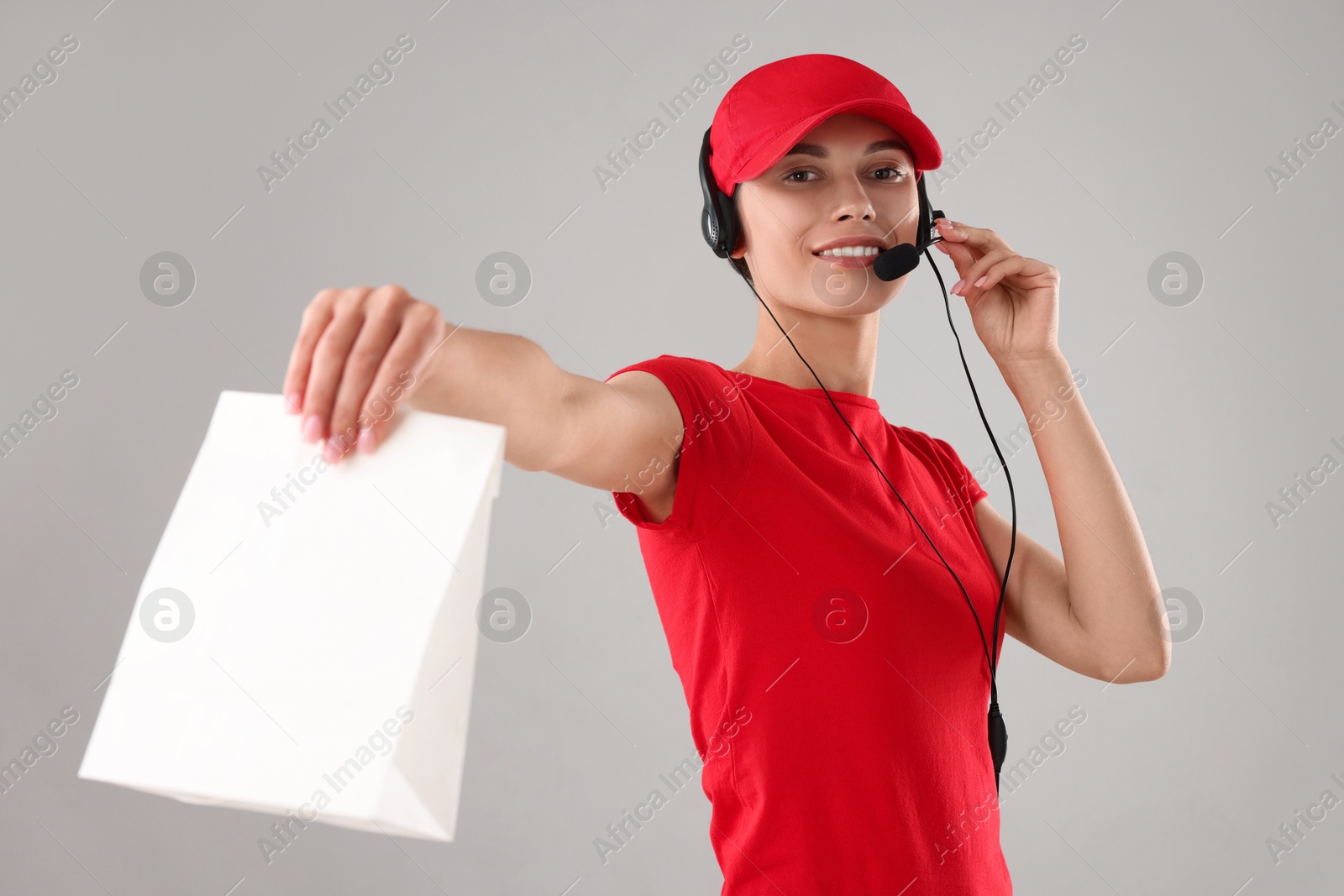 Photo of Fast-food worker with paper bag on gray background