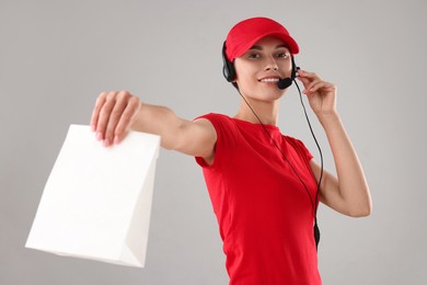 Photo of Fast-food worker with paper bag on gray background