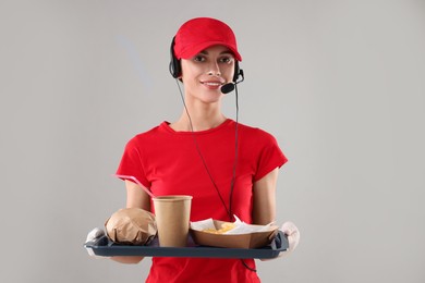 Photo of Fast-food worker holding tray with order on gray background,