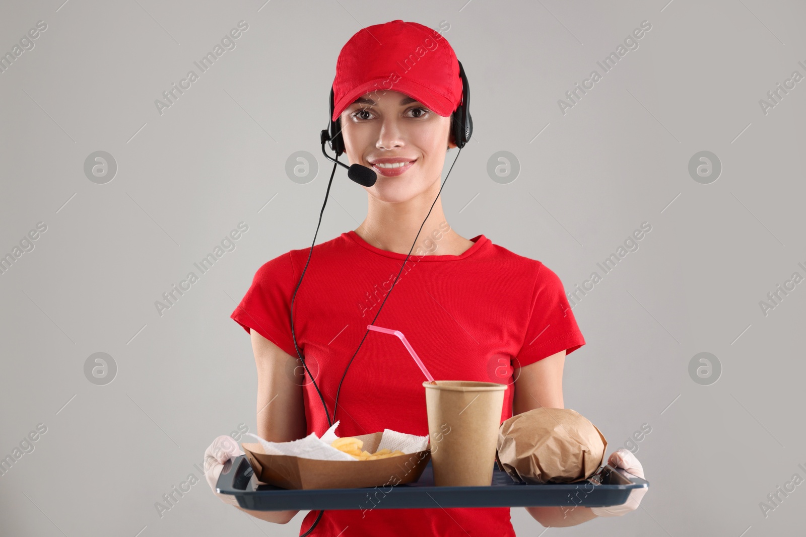 Photo of Fast-food worker holding tray with order on gray background,