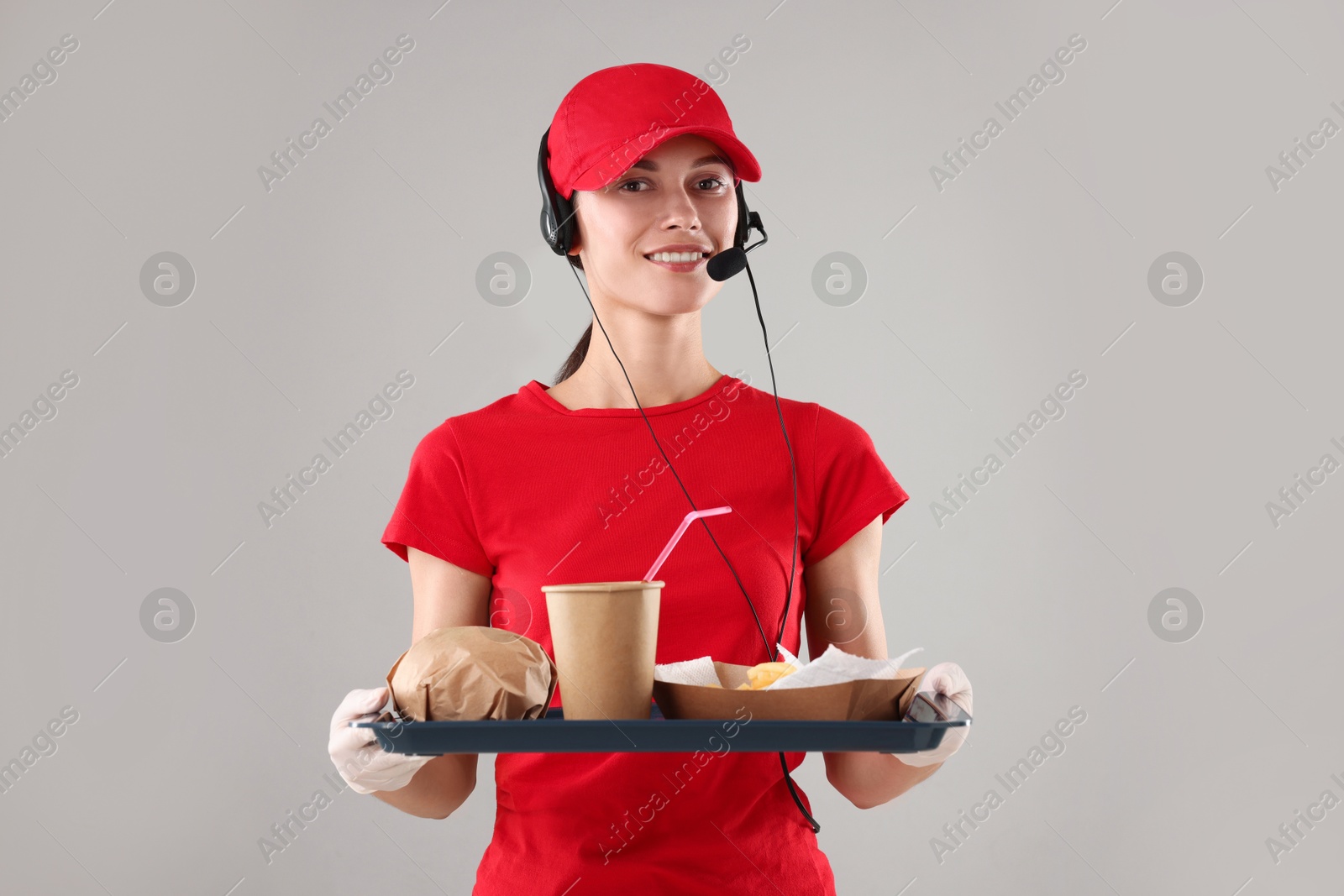 Photo of Fast-food worker holding tray with order on gray background,