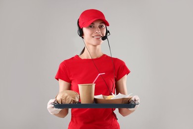 Photo of Fast-food worker holding tray with order on gray background,