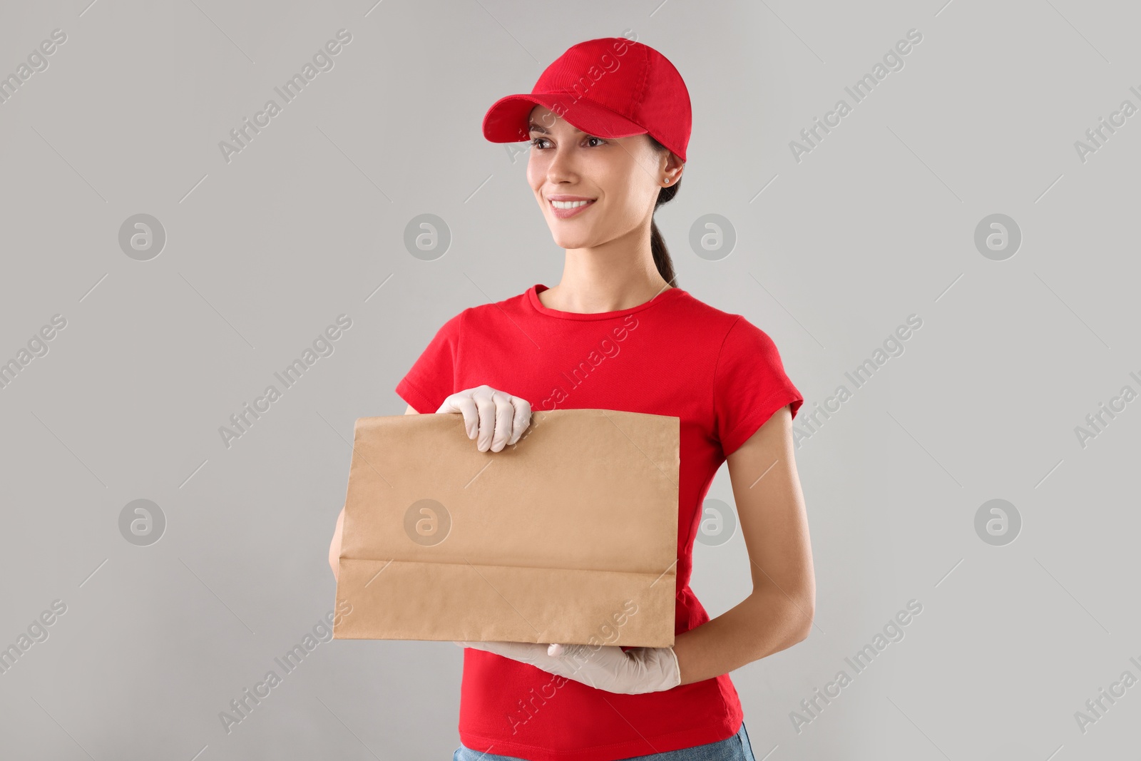 Photo of Fast-food worker with paper bag on gray background