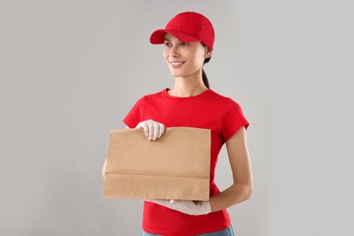 Fast-food worker with paper bag on gray background