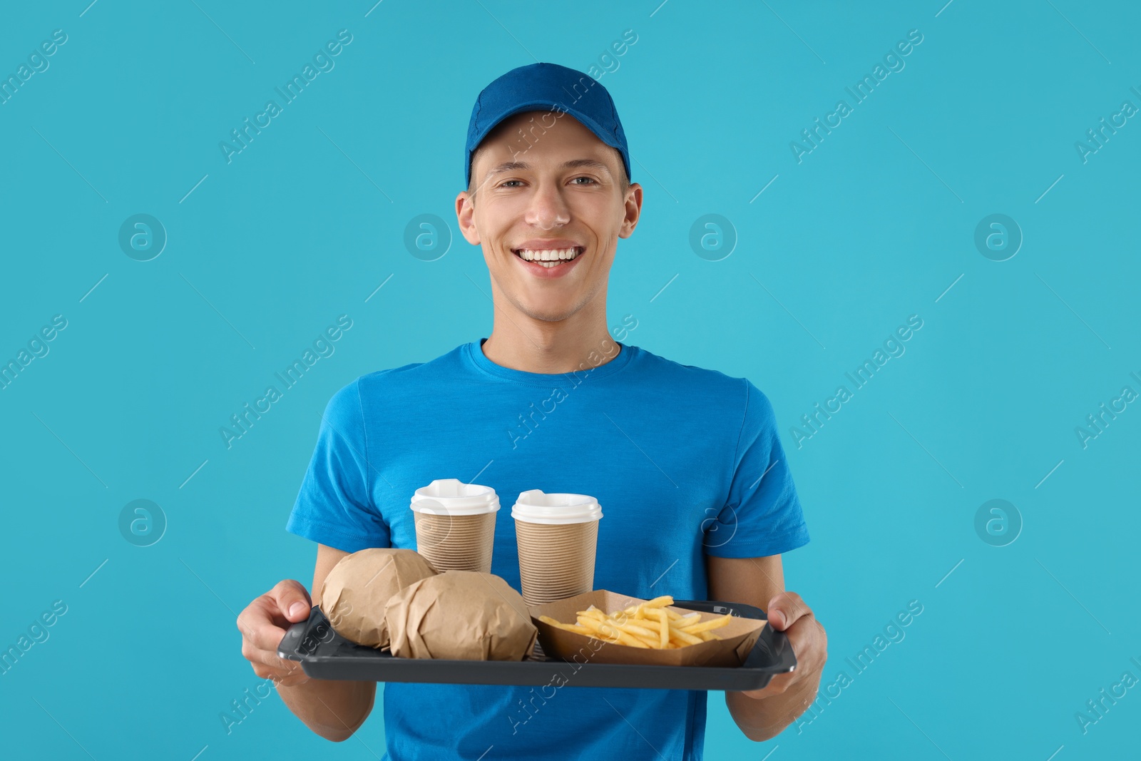 Photo of Fast-food worker holding tray with order on light blue background