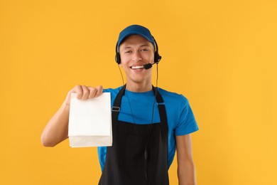 Fast-food worker with paper bag on orange background