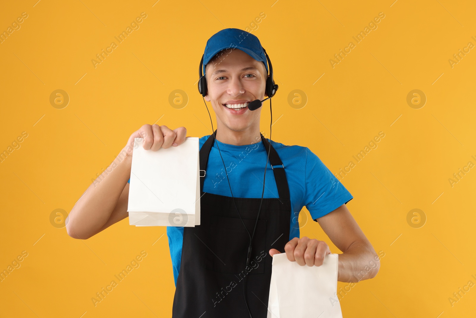 Photo of Fast-food worker with paper bags on orange background