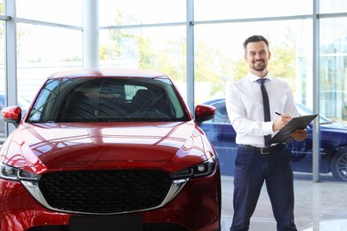 Happy salesman near new red car in salon