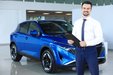 Happy salesman near new blue car in salon