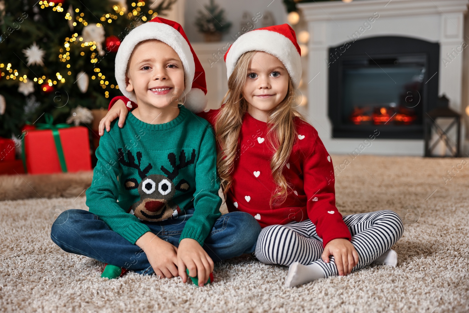 Photo of Cute little kids with Santa hats in room decorated for Christmas