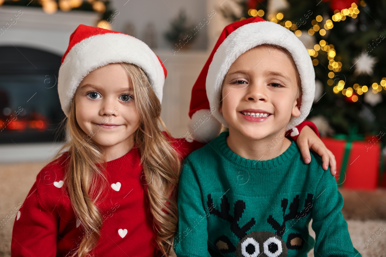 Photo of Cute little kids with Santa hats in room decorated for Christmas