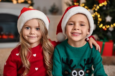 Photo of Cute little kids with Santa hats in room decorated for Christmas