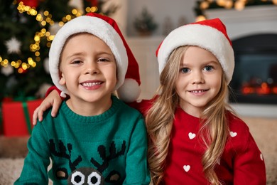 Photo of Cute little kids with Santa hats in room decorated for Christmas