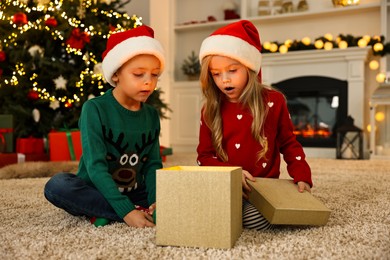 Photo of Little kids opening magic Christmas box on floor at home