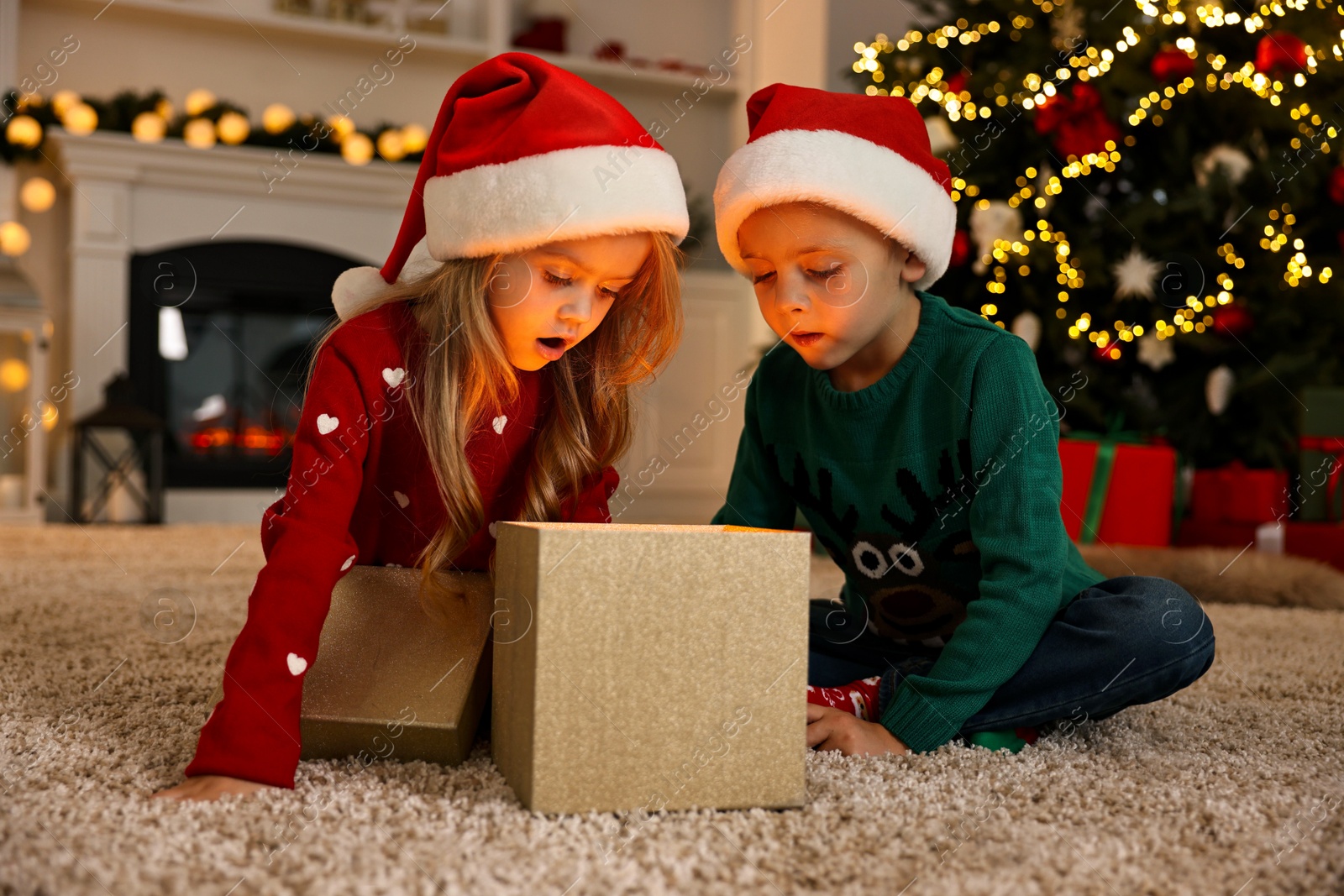 Photo of Little kids opening magic Christmas box on floor at home