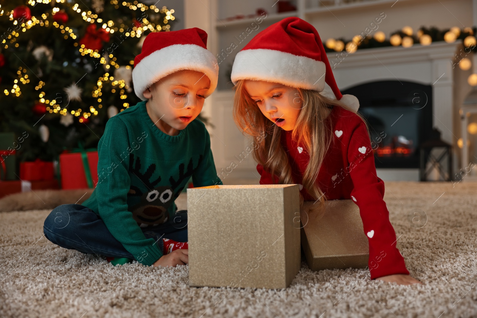 Photo of Little kids opening magic Christmas box on floor at home