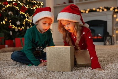 Photo of Little kids opening magic Christmas box on floor at home