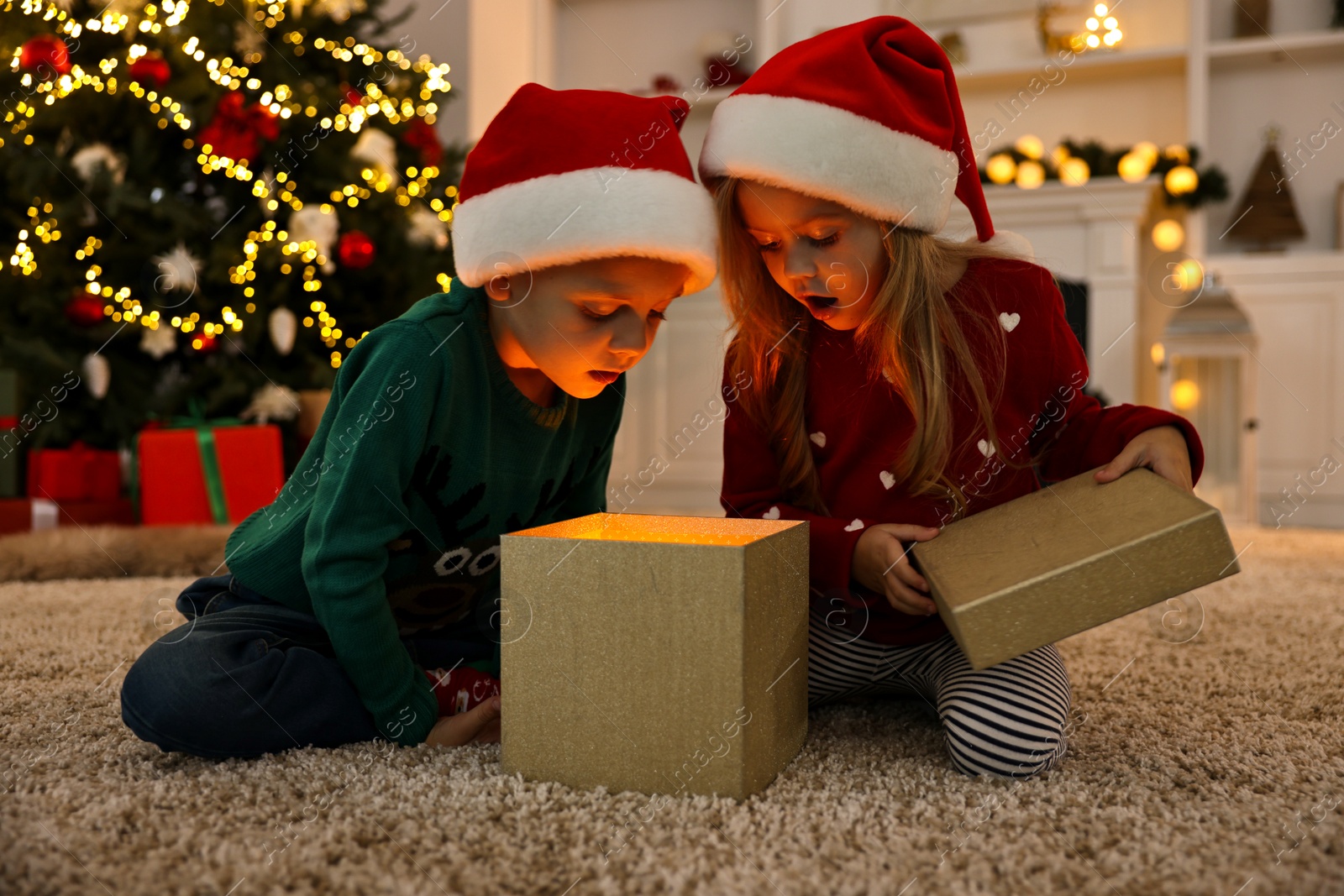 Photo of Little kids opening magic Christmas box on floor at home